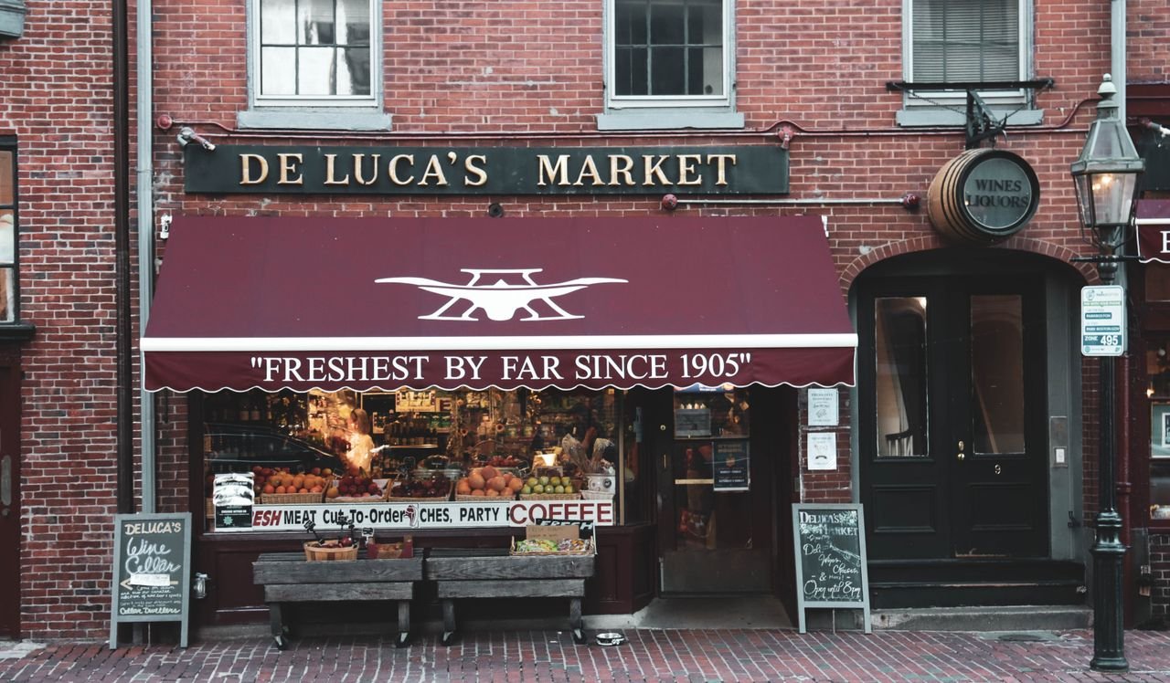 Historic De Luca's Market facade showcasing fresh produce and cozy urban atmosphere.